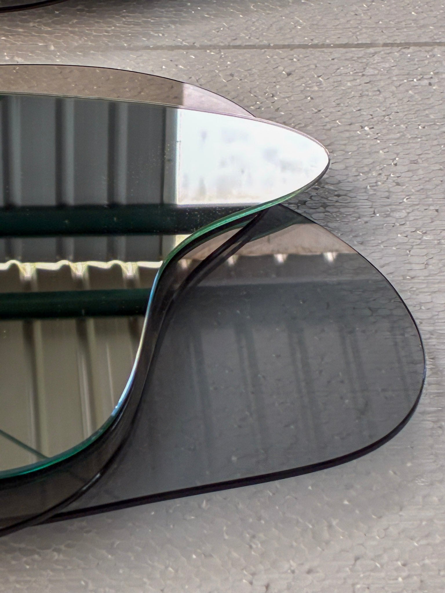Detalle del borde pulido al agua del espejo Tríada, mostrando la unión técnica de sus tres capas de cristal.